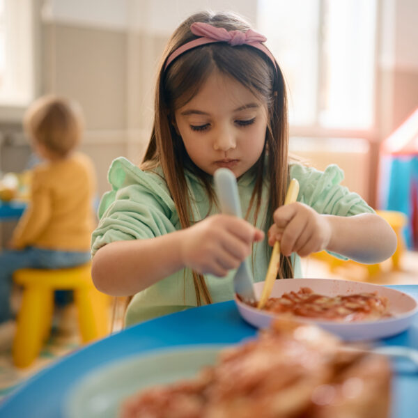 Little girl eating lunch at kindergarten.